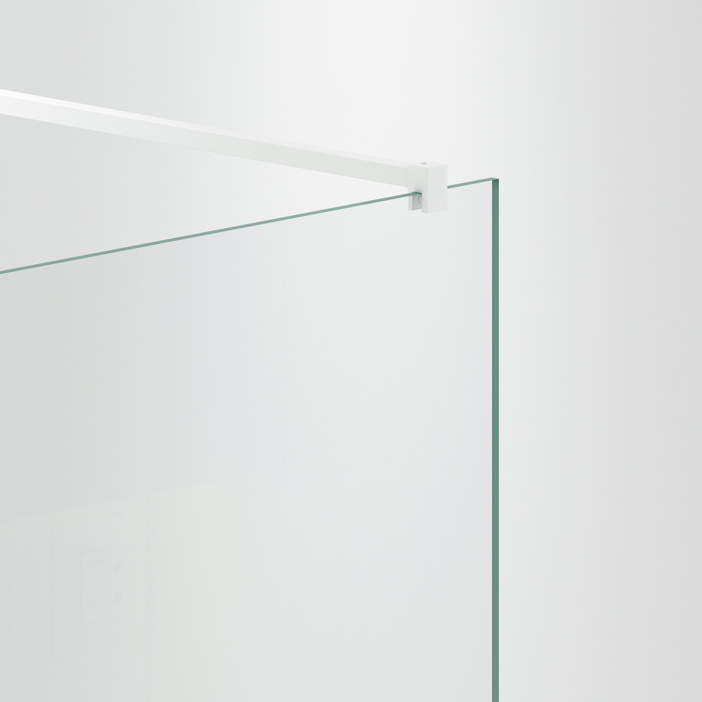 Minimalist frameless walk-in shower room with single fixed glass panel and slim support bar, creating an open and modern bathroom space